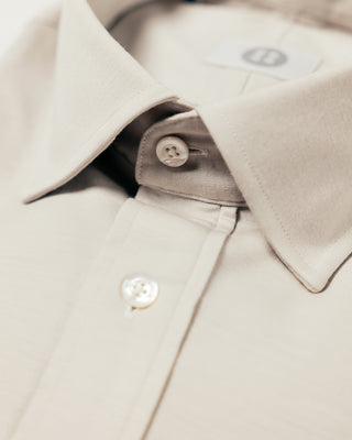 Close-up of a beige trench coat with buttons on a light background