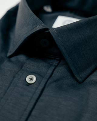 Close-up of a dark blue shirt with a button and collar detail.