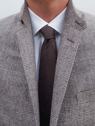 Gray checkered blazer with a white shirt and brown tie on a light gray background